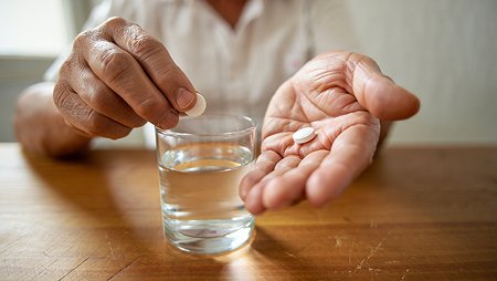 В руке лежит белая таблетка